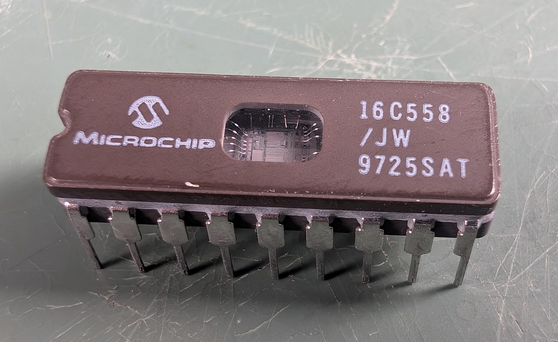 A Microchip PIC-series microcontroller in a ceramic DIP package, the silicon die visible through its window