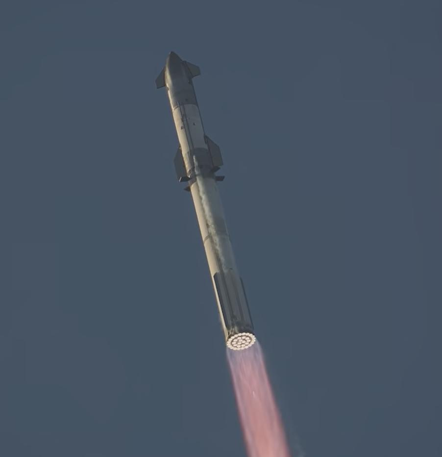 Starship ascending against a clear blue sky, its engine plume glowing below the vehicle