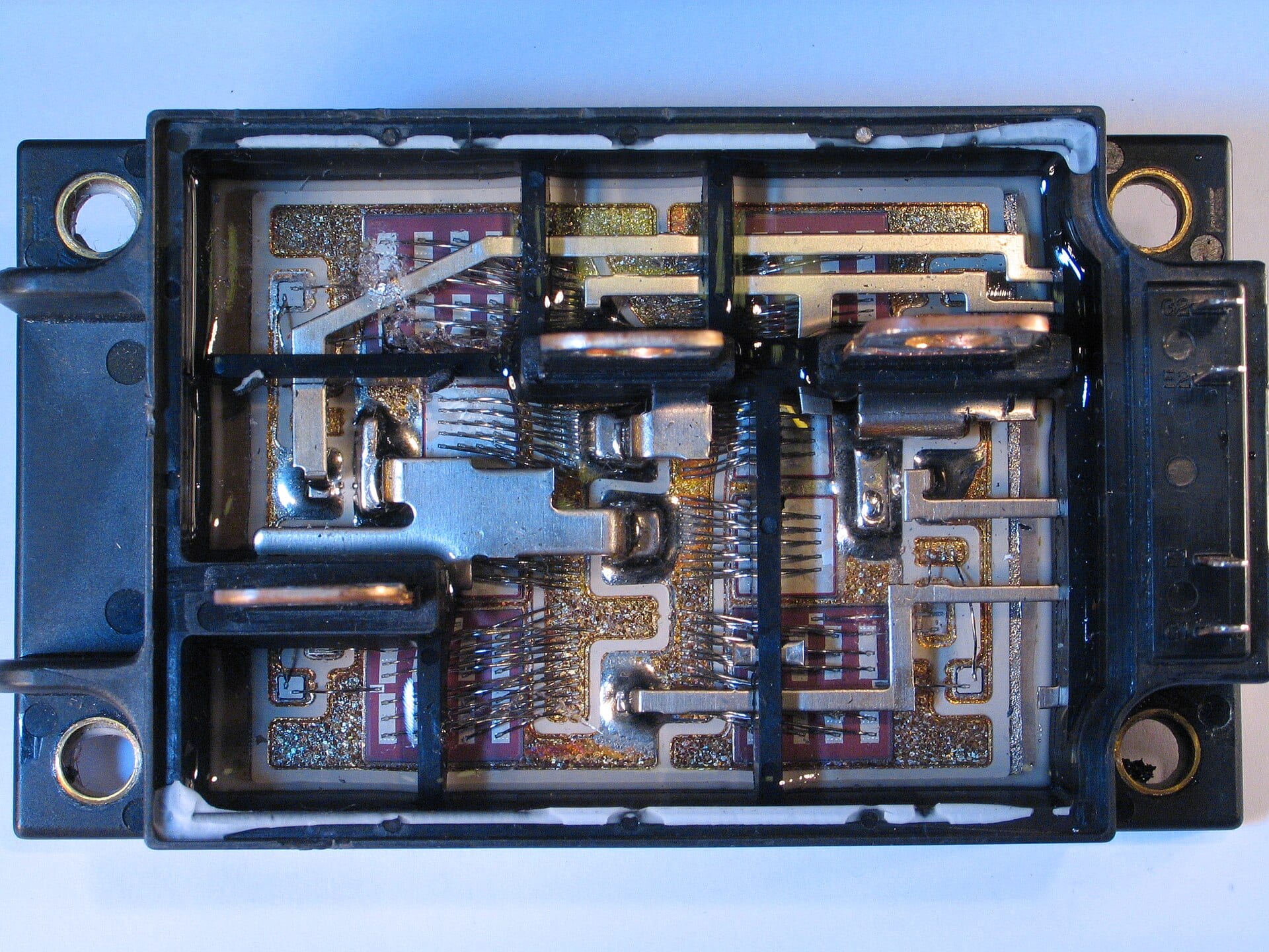 An opened power semiconductor module showing switching dies, bond wires and copper busbars inside a black plastic housing