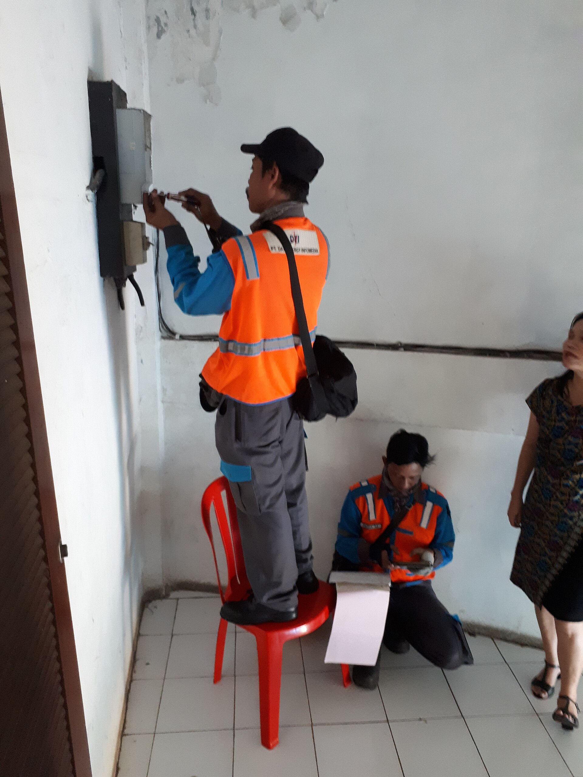 Electricians repairing an electricity meter on a household wall