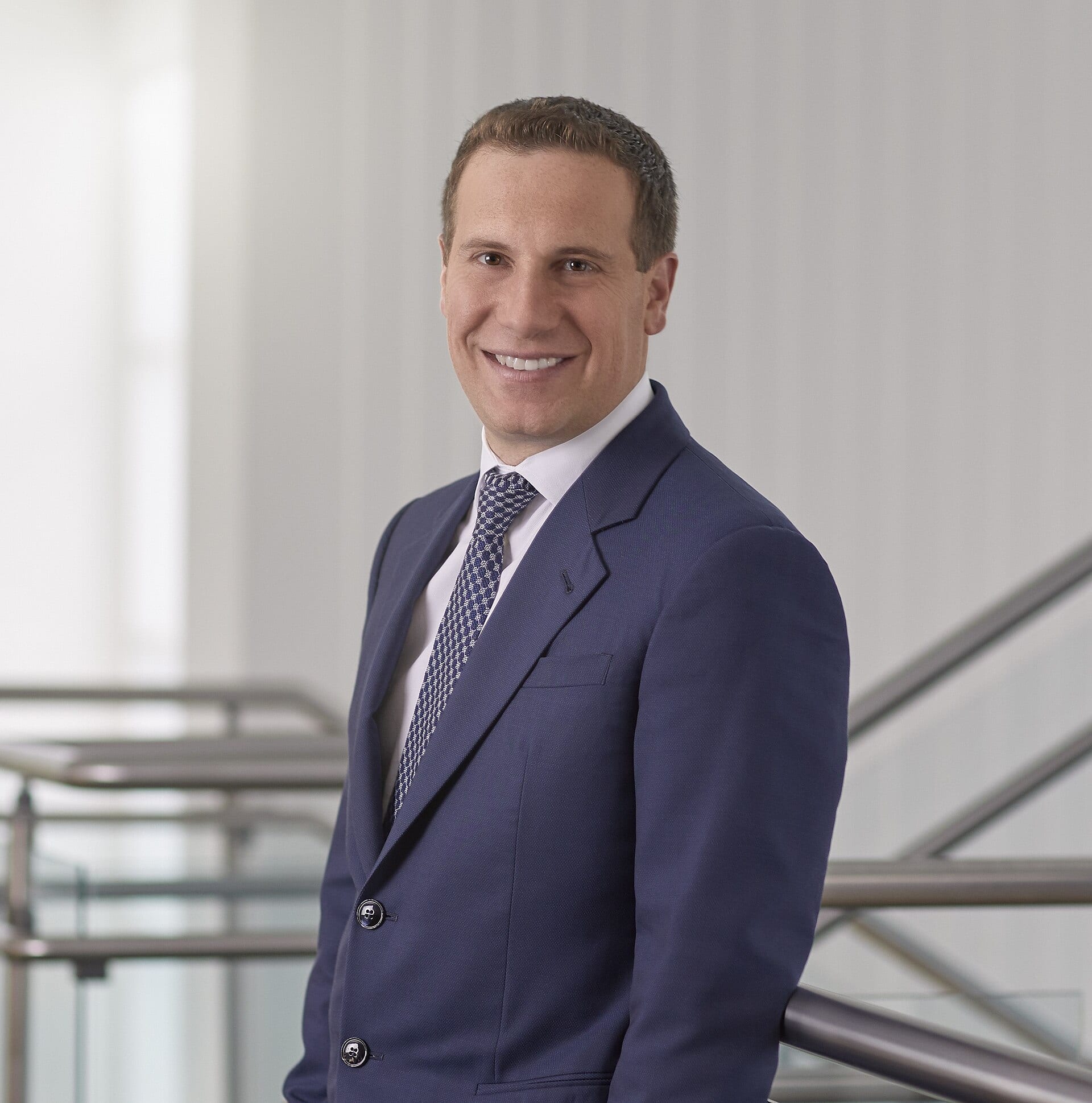 Mat Ishbia, chief executive of UWM Holdings, smiling in a navy suit on a staircase at his company's headquarters