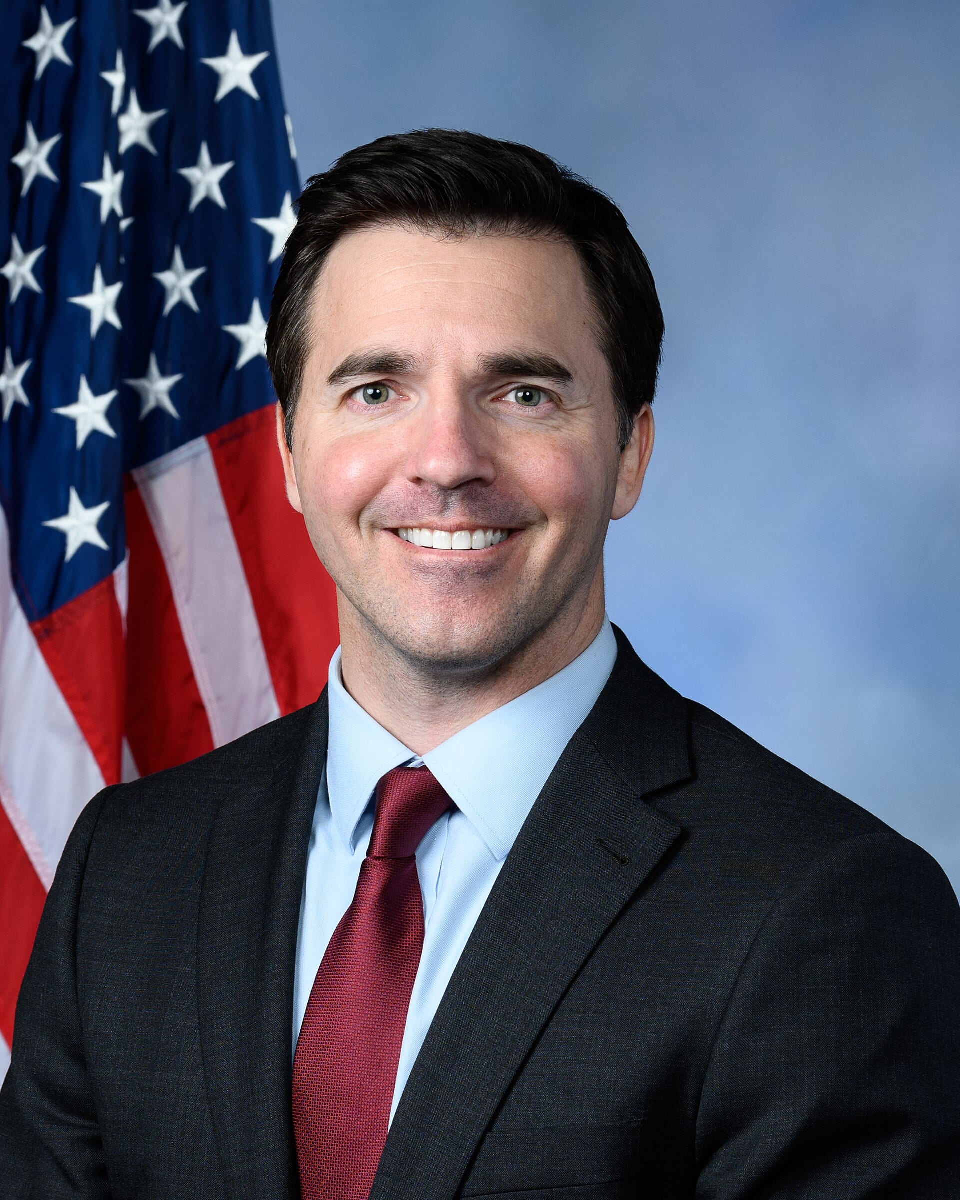 Official portrait of Jeff Jackson, North Carolina attorney general, in a suit before an American flag