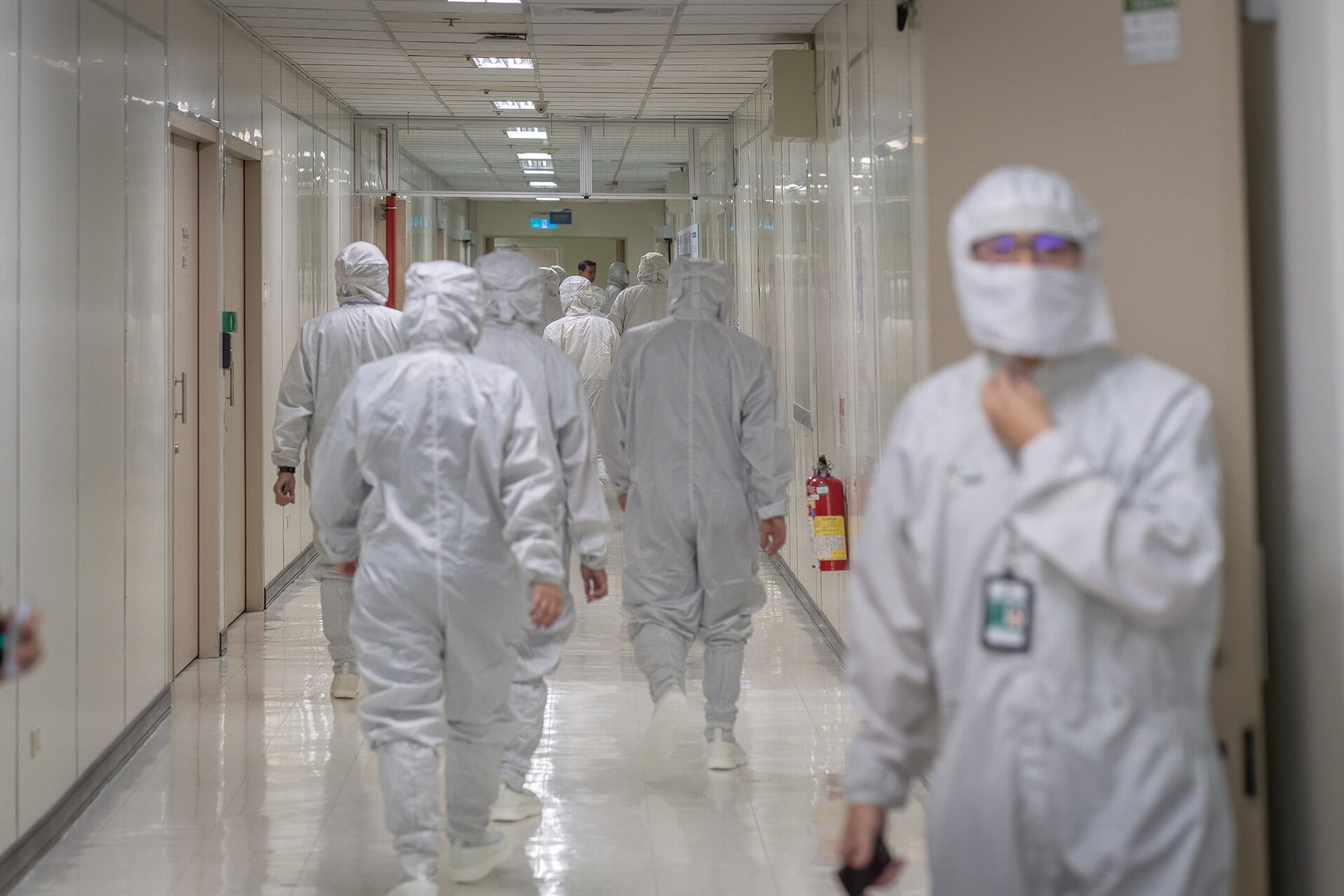 Visitors and staff in cleanroom suits walking a corridor inside an ASE semiconductor plant in Taiwan