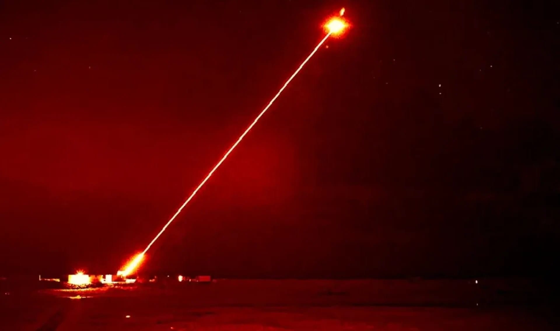 A high-energy laser weapon fires a beam into the sky during a night trial