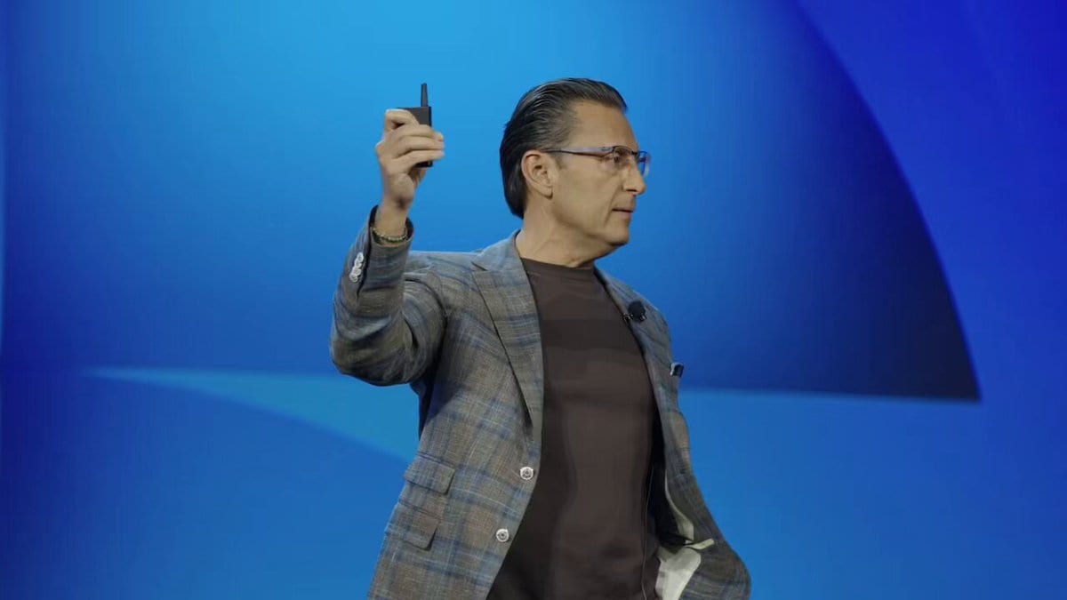 Intuit CEO Sasan Goodarzi on stage at Intuit Connect, holding a clicker against a blue backdrop