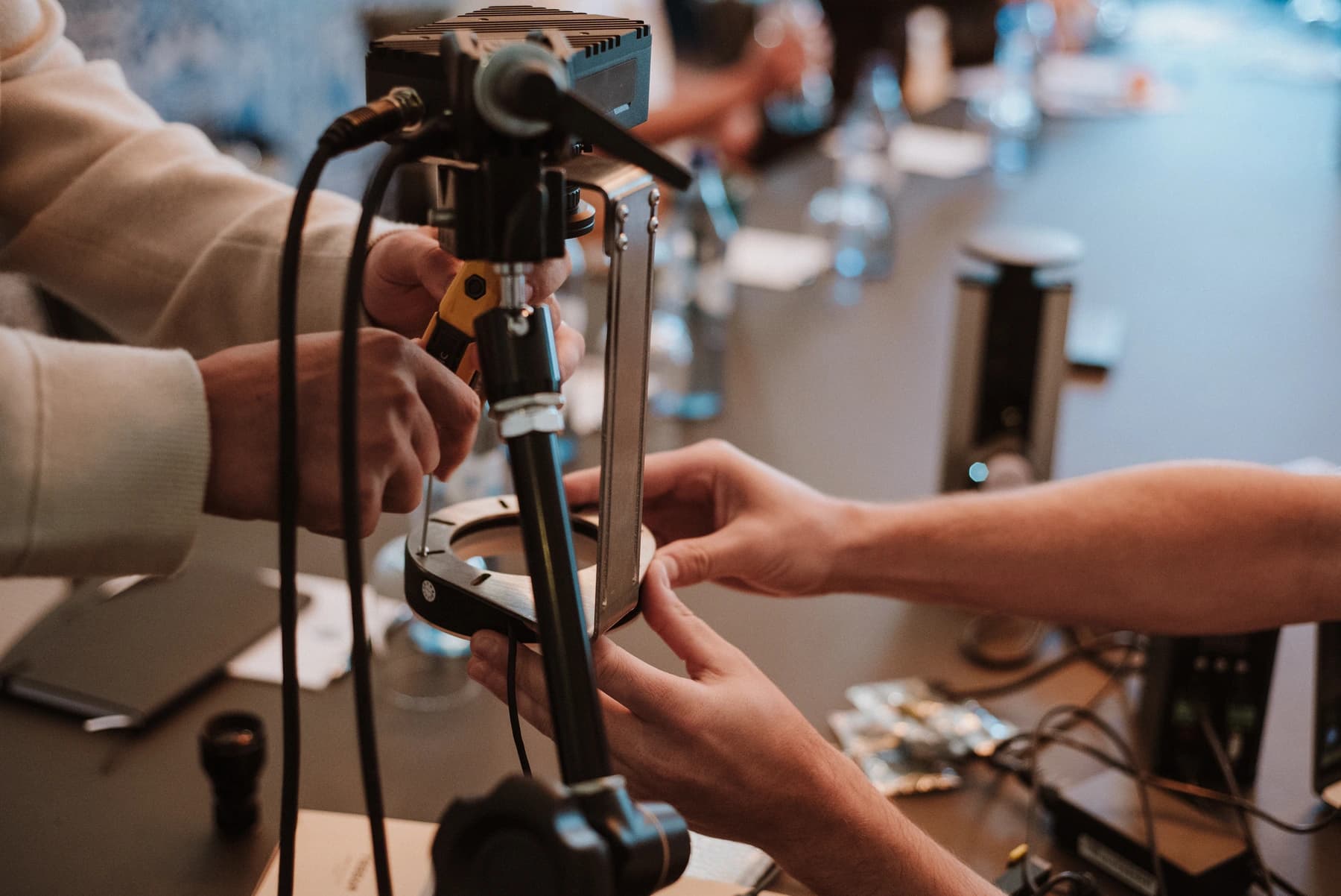 Two people mounting an Overview camera and ring light above a workbench