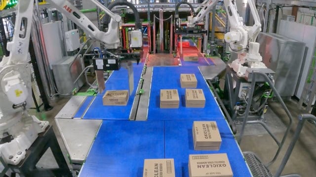 Robotic arms moving boxes on a conveyor at an automated warehouse picking line