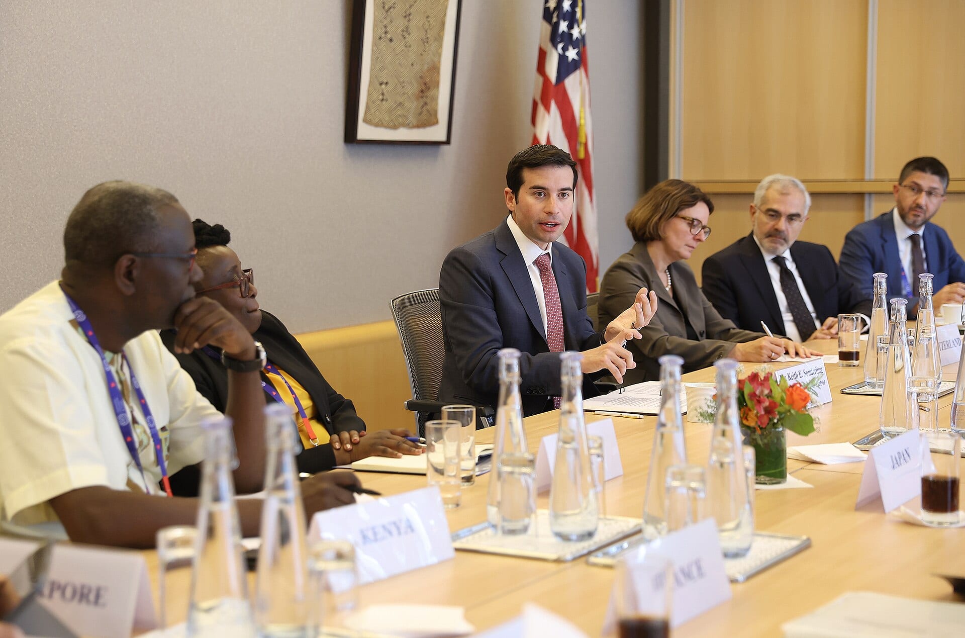US Labor Secretary Keith Sonderling speaking at a roundtable table in Geneva, nameplate before him