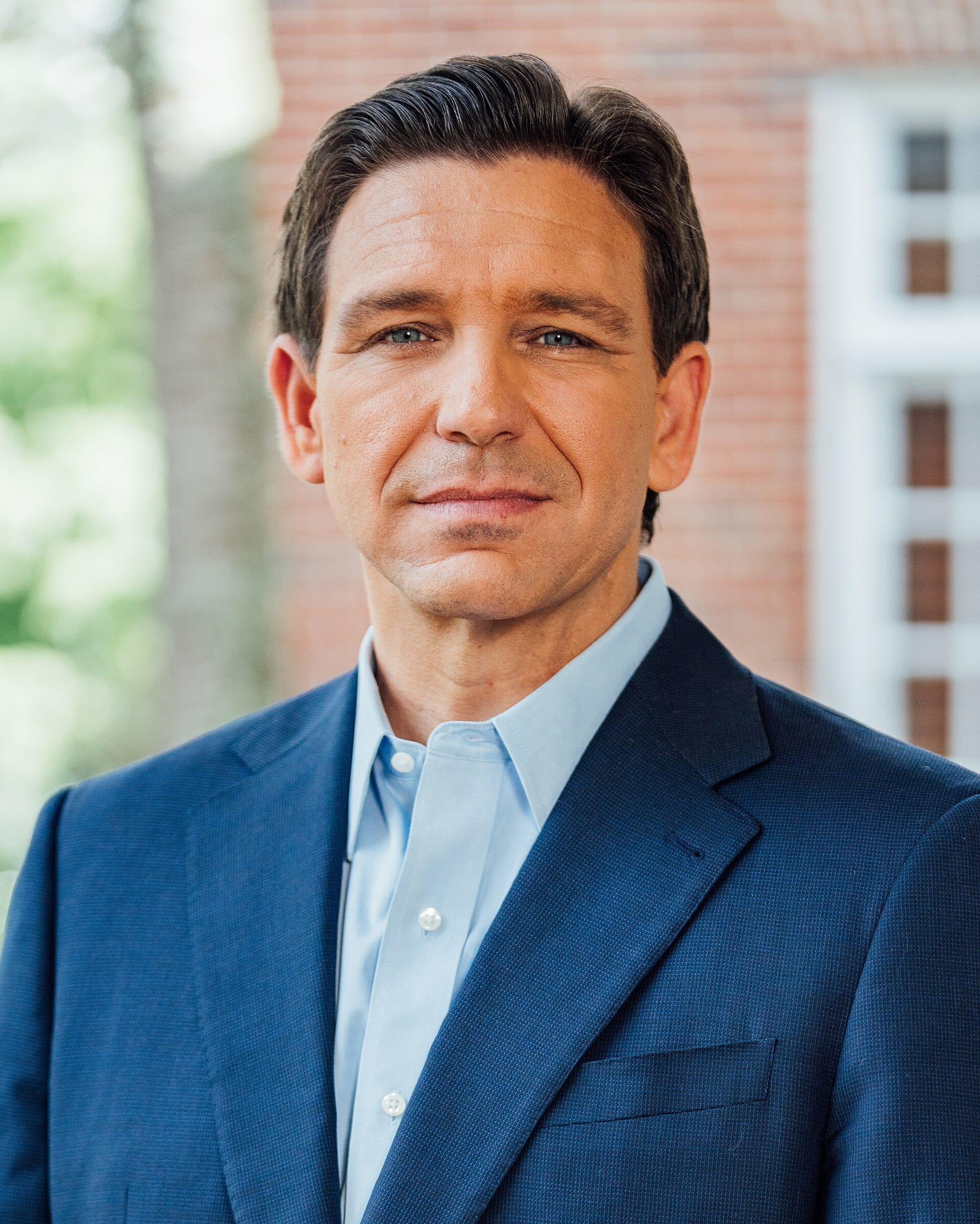 Official portrait of Florida governor Ron DeSantis in a blue suit, smiling slightly.