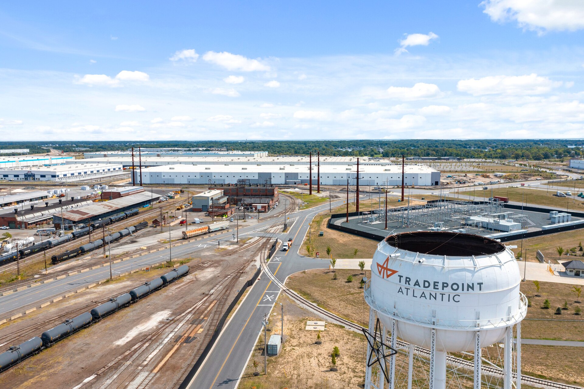 Aerial view of Tradepoint Atlantic at Sparrows Point, with rail lines, distribution warehouses and a water tower bearing the Tradepoint Atlantic name