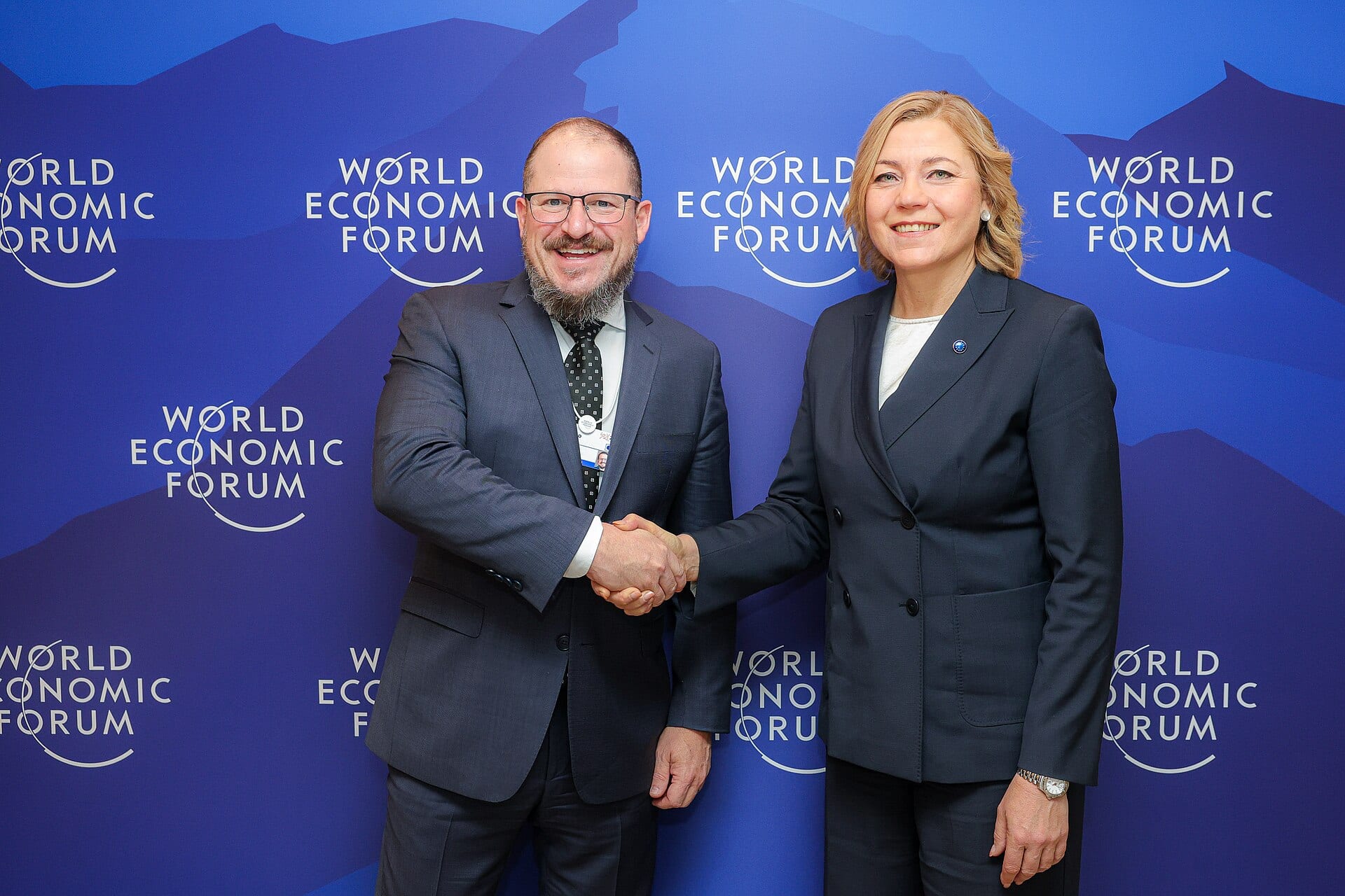 Qualcomm CEO Cristiano Amon shakes hands with a European Commission official at the World Economic Forum