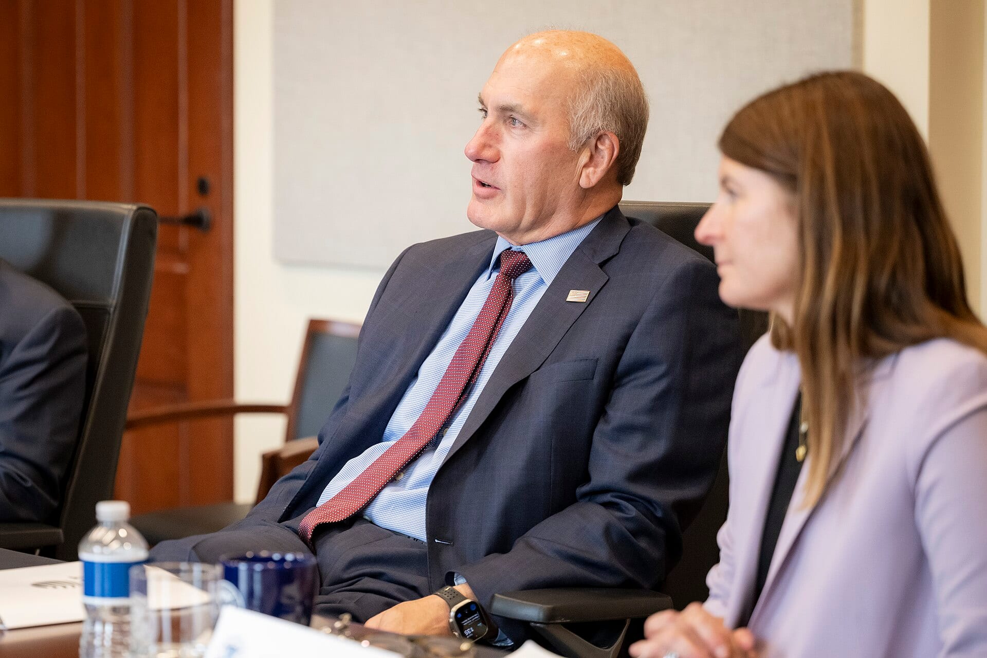 AT&T chairman John Stankey, in a dark suit and red tie, seated and speaking at a meeting at Department of Homeland Security headquarters in June 2025.