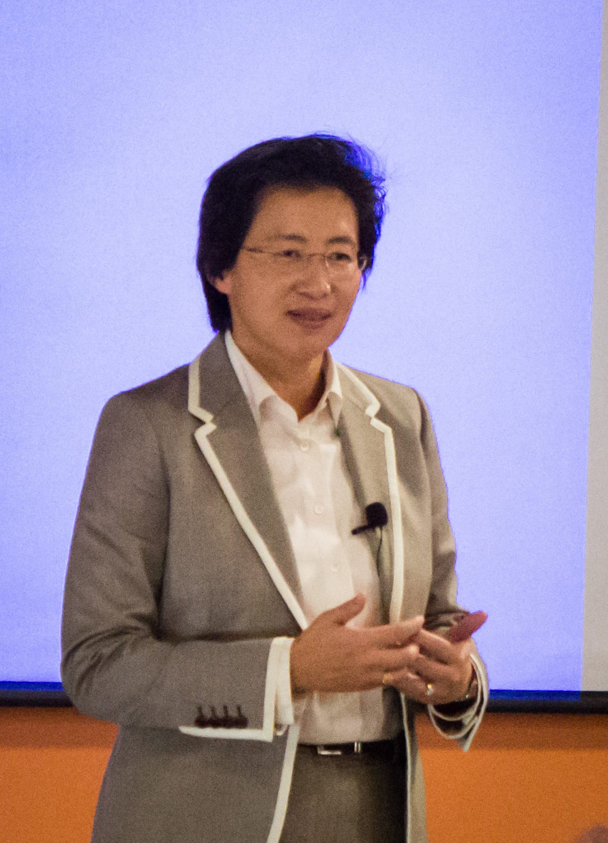 AMD chief executive Lisa Su speaking on stage in a gray blazer, wearing glasses