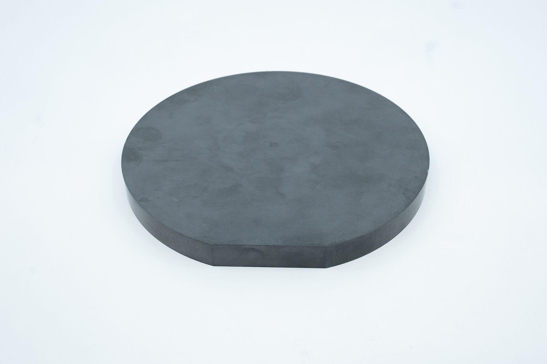 A rounded silicon carbide ingot, a dark grey disc with one flat edge, on a white background.