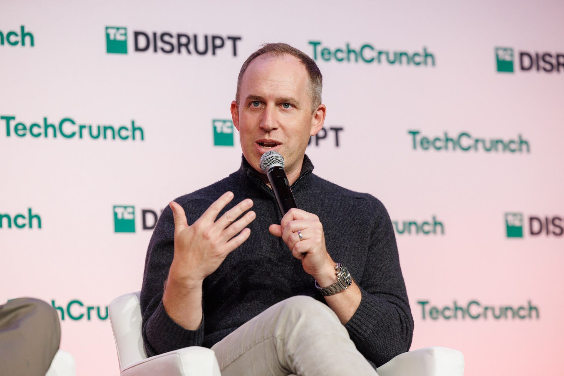 Bret Taylor speaking into a microphone on stage at TechCrunch Disrupt 2024, gesturing with his left hand