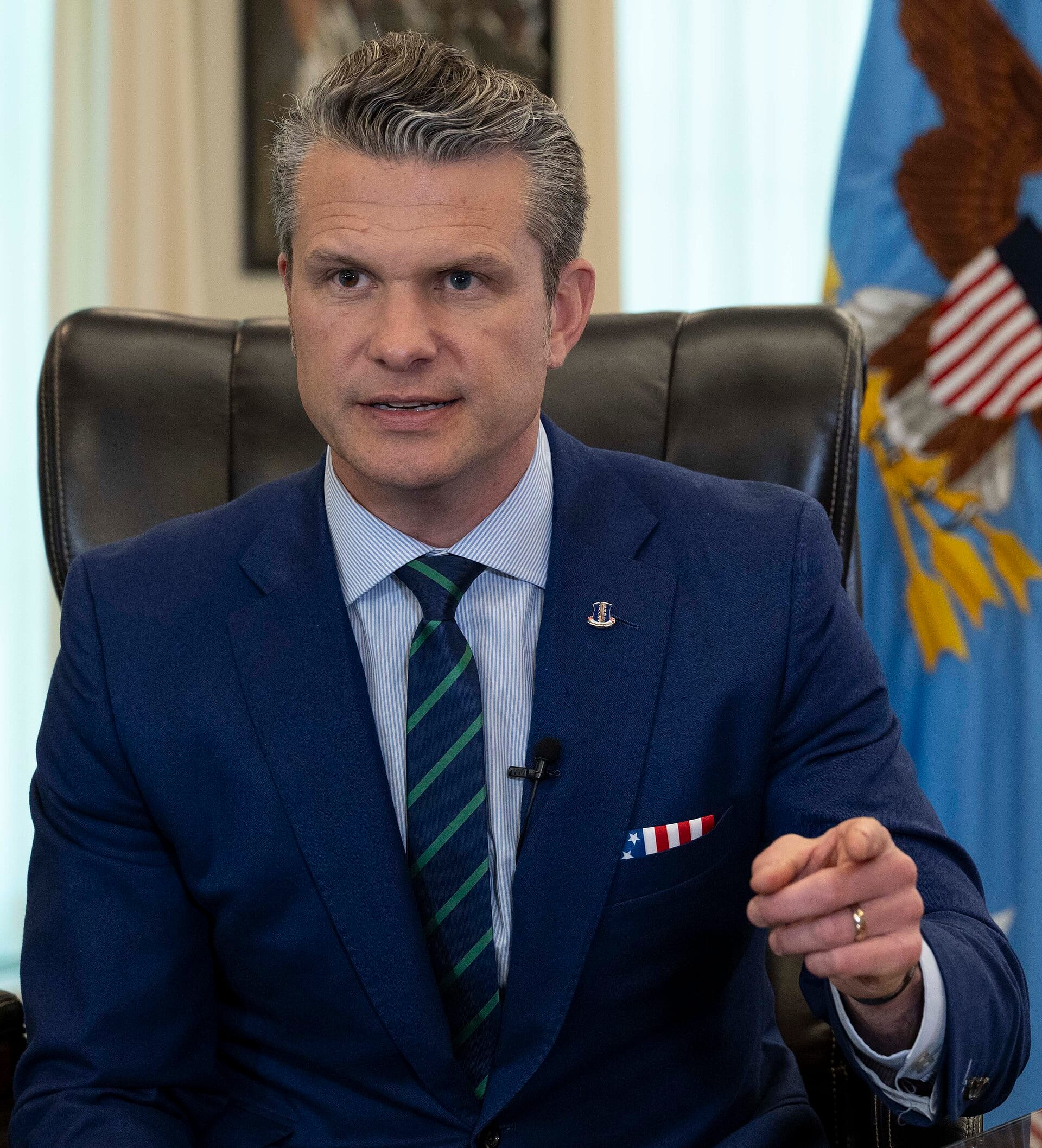 Defense Secretary Pete Hegseth in an official portrait, seated at a desk.