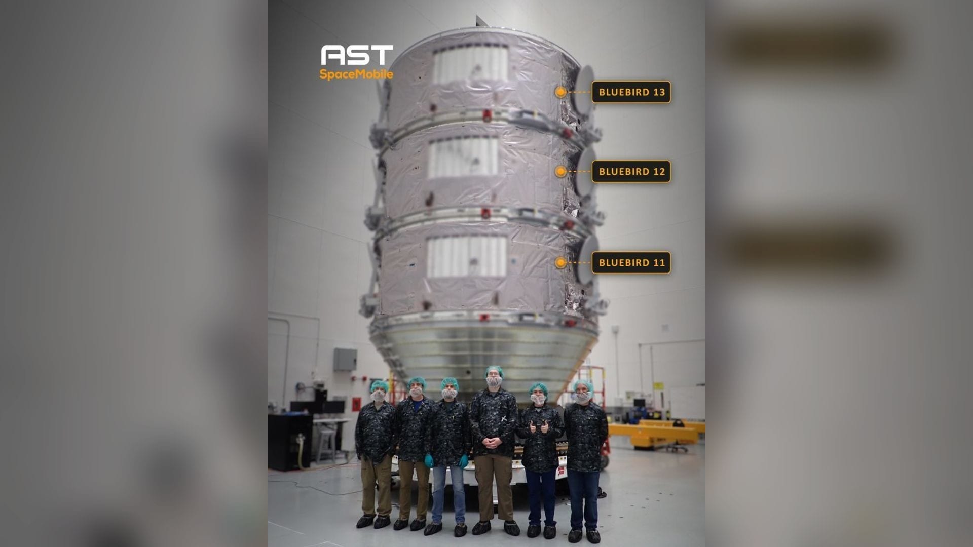 AST SpaceMobile technicians in cleanroom gear stand before BlueBird satellites 11, 12 and 13 stacked for launch at Cape Canaveral
