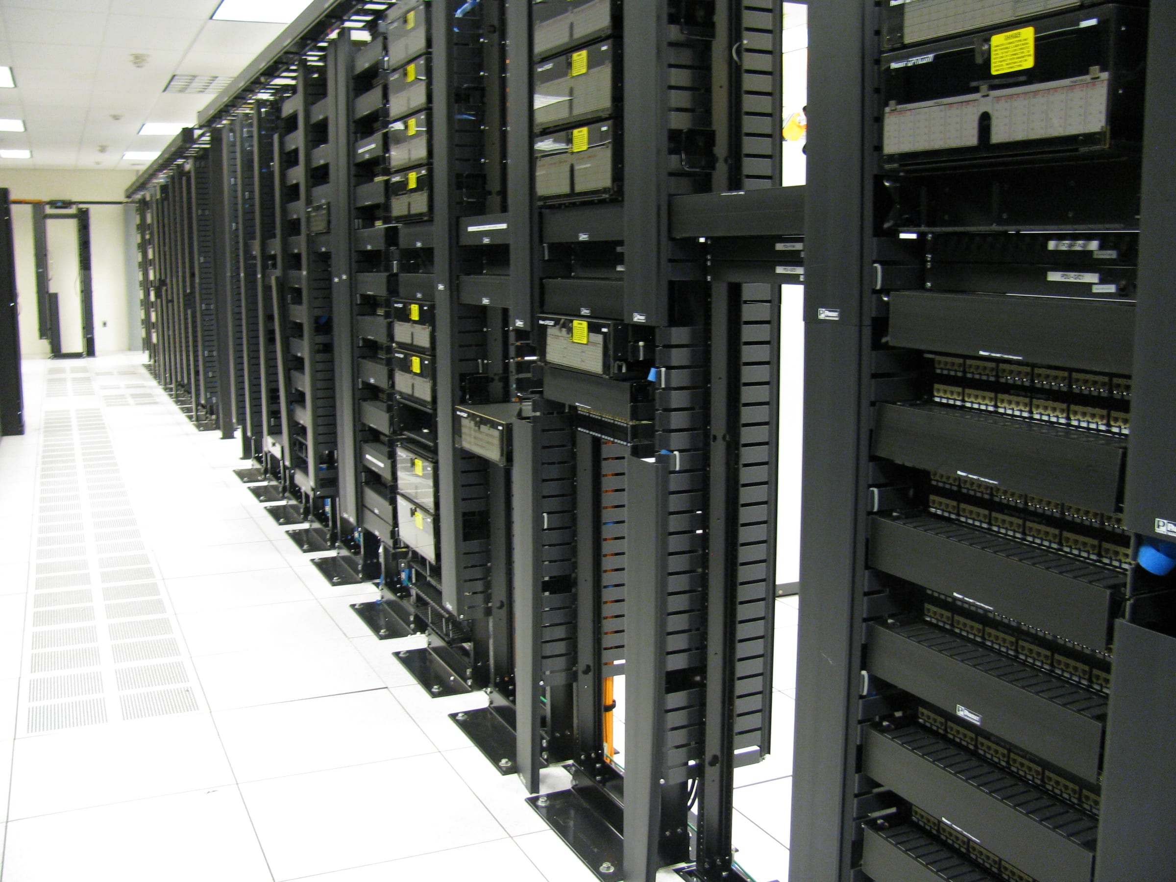 Racks of servers and cabling along the cold aisle of a data center, the kind of mechanical and electrical work Comfort Systems installs