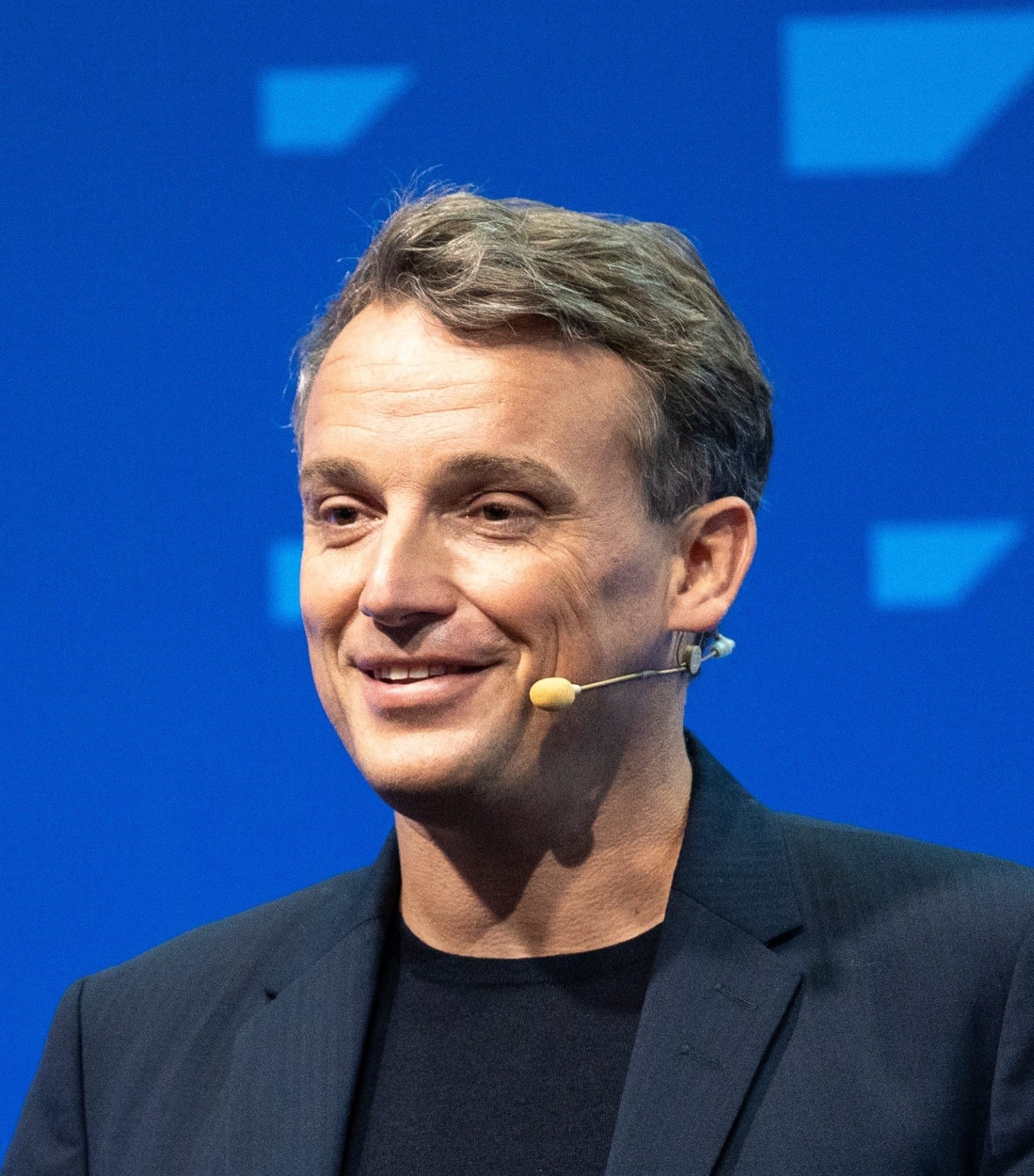 Christian Klein, chief executive of SAP, speaking on stage into a headset microphone against a blue backdrop.