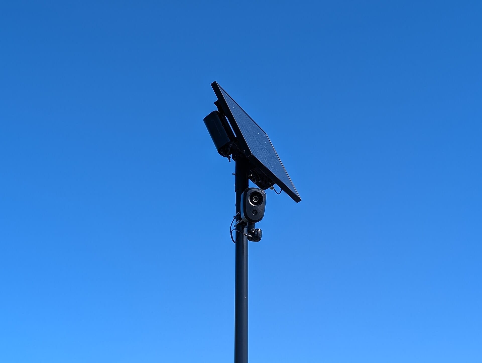 A Flock Safety automated license plate reader camera mounted on a pole against a blue sky in West Long Branch, New Jersey, October 2026.