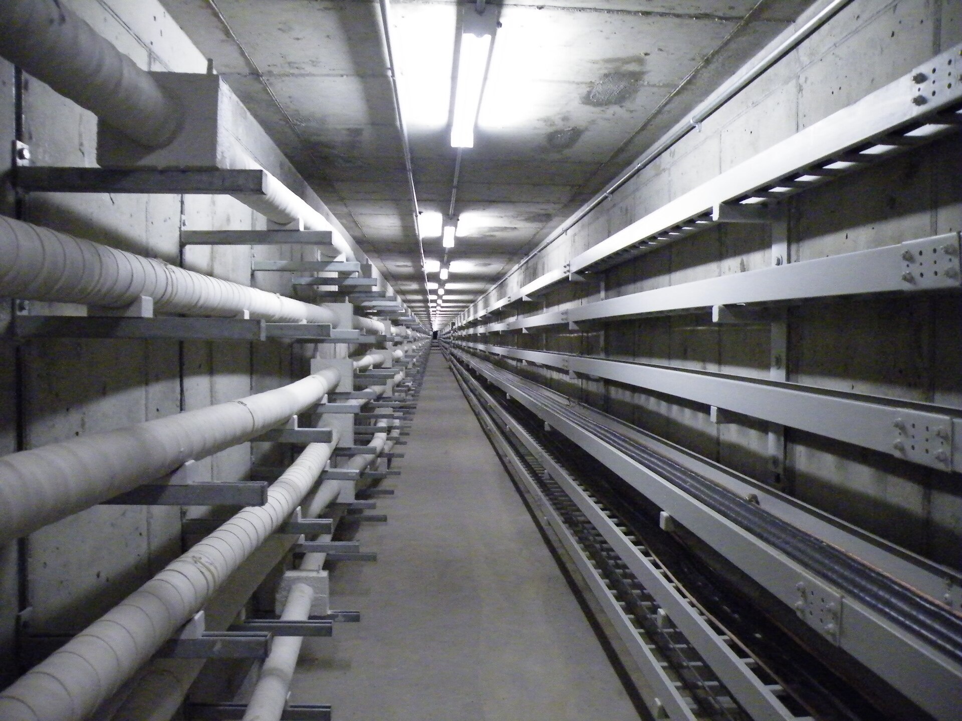 High-voltage power cables racked inside a concrete utility tunnel