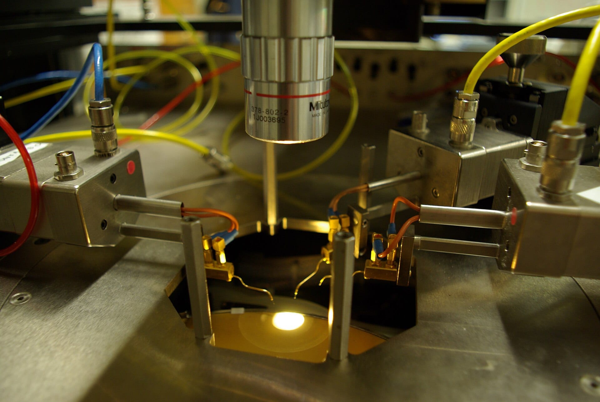 Probe tips contacting a silicon die under a microscope on a wafer probe station