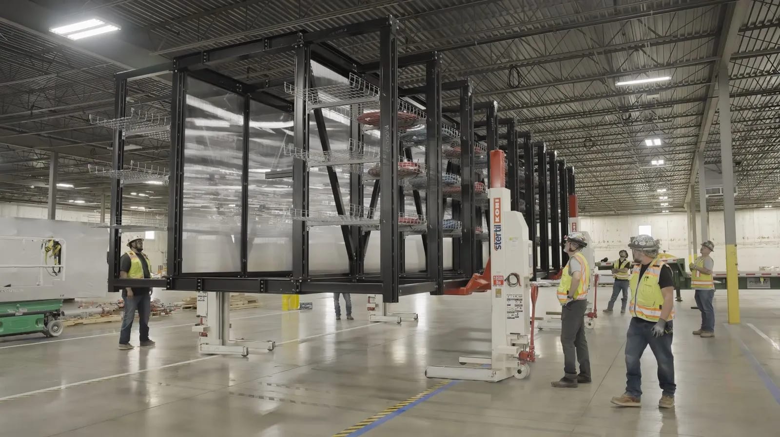 Workers moving a factory-built modular data center infrastructure platform inside an Accelevation manufacturing facility