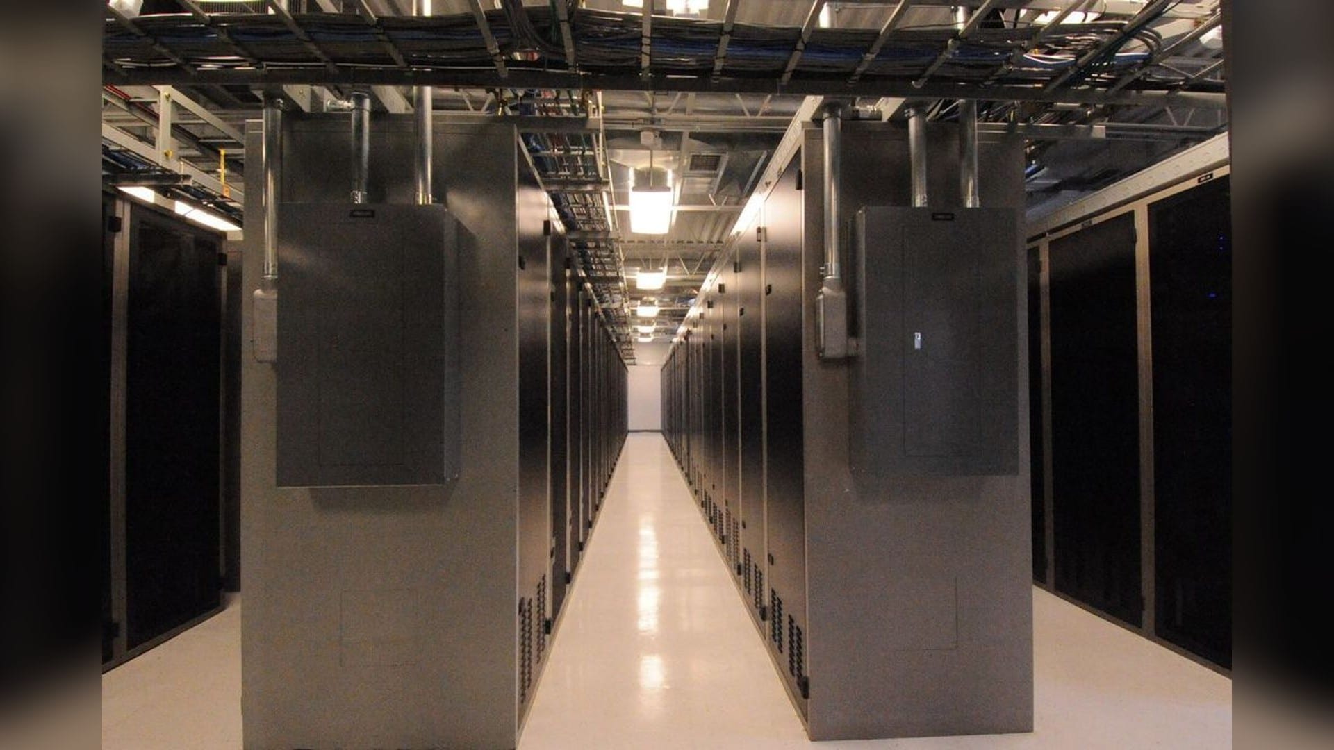 Power panels above server racks along a data-center aisle