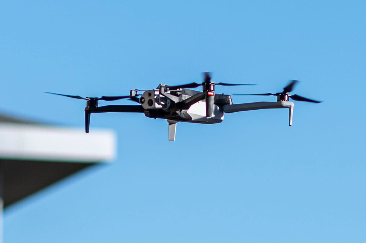 A Skydio X10 quadcopter flying against a clear blue sky