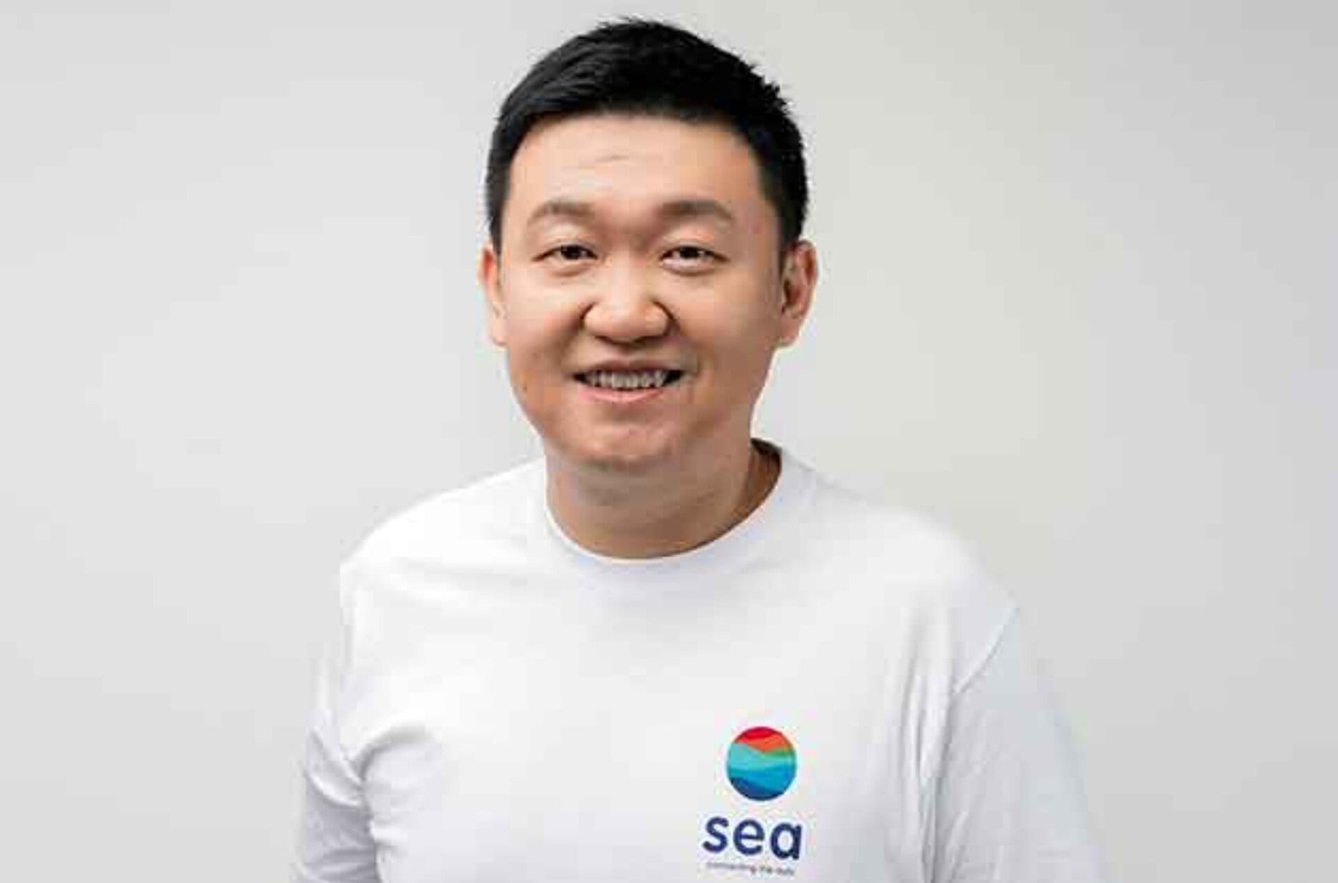 Forrest Li, founder, chairman and chief executive of Sea Limited, smiling in a white Sea t-shirt against a plain grey background