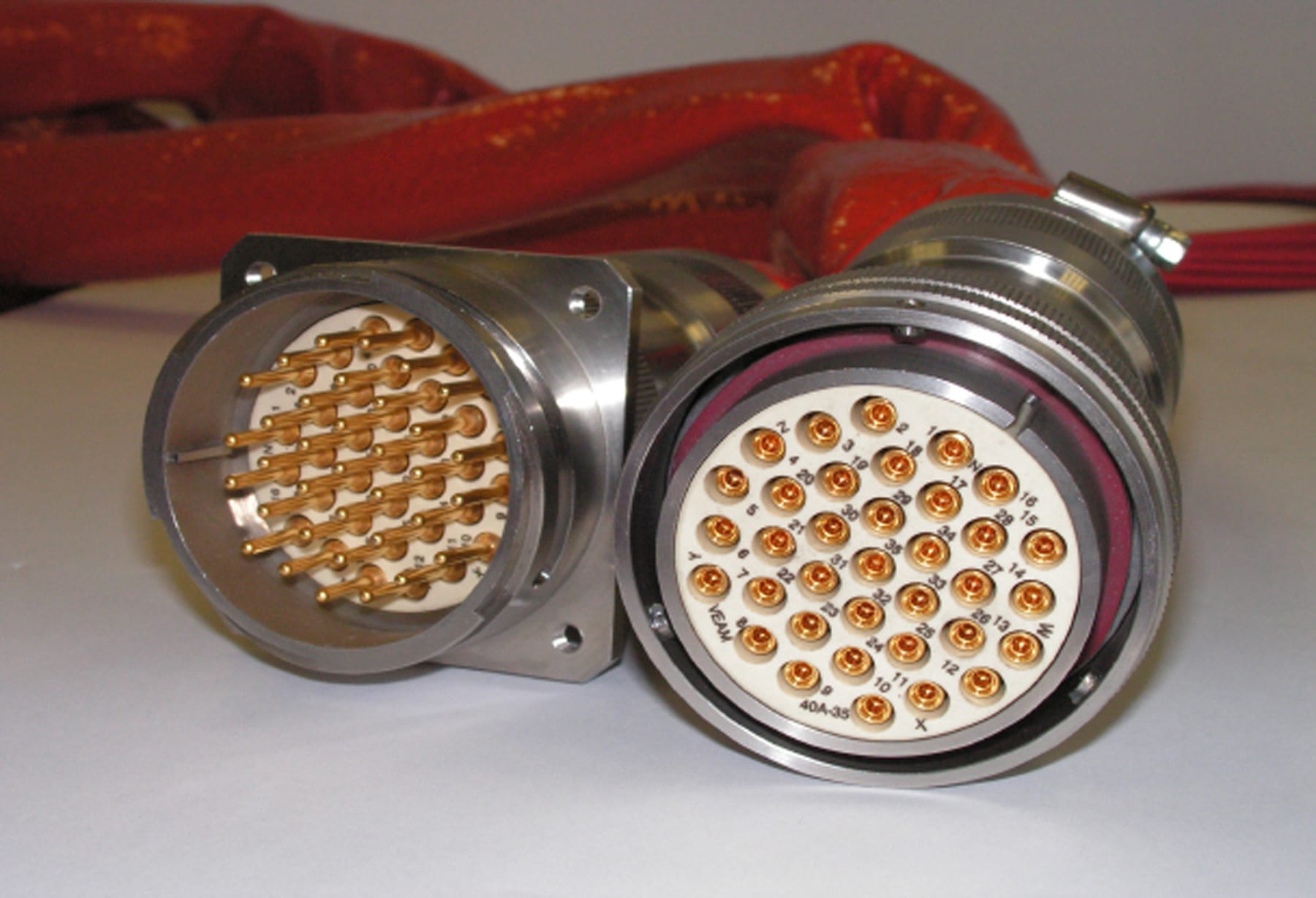 A circular multi-pin industrial electrical connector with gold-plated contacts, shown from the mating side