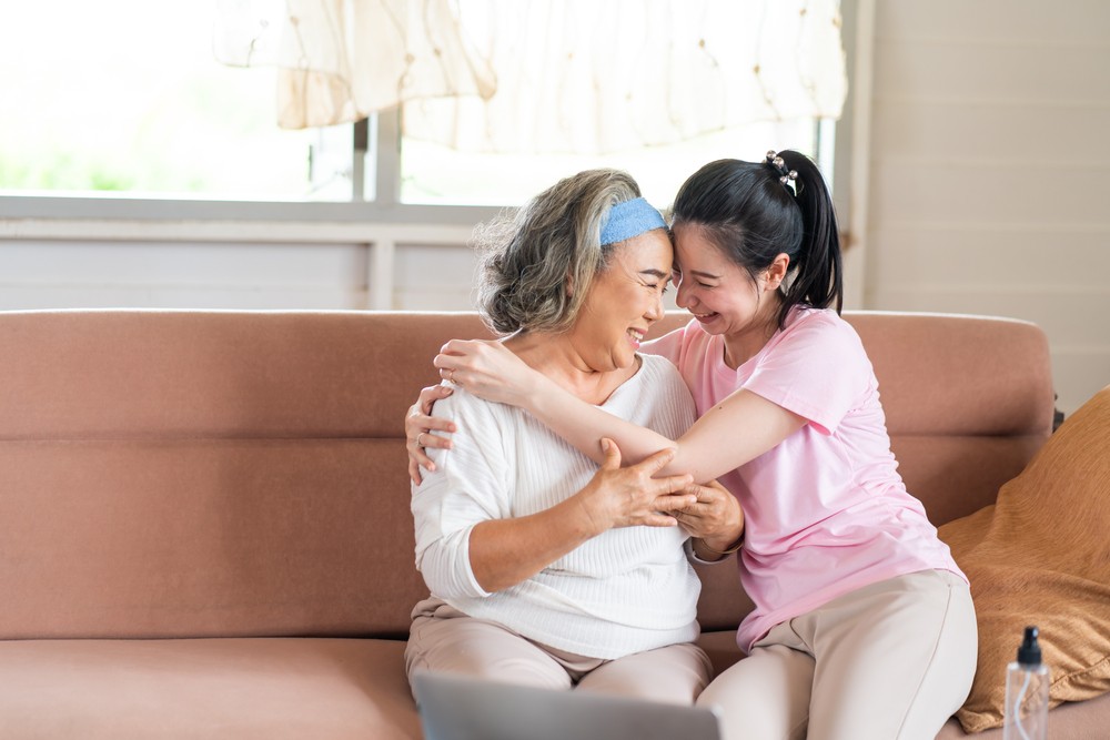 Senior woman embracing daughter on the couch