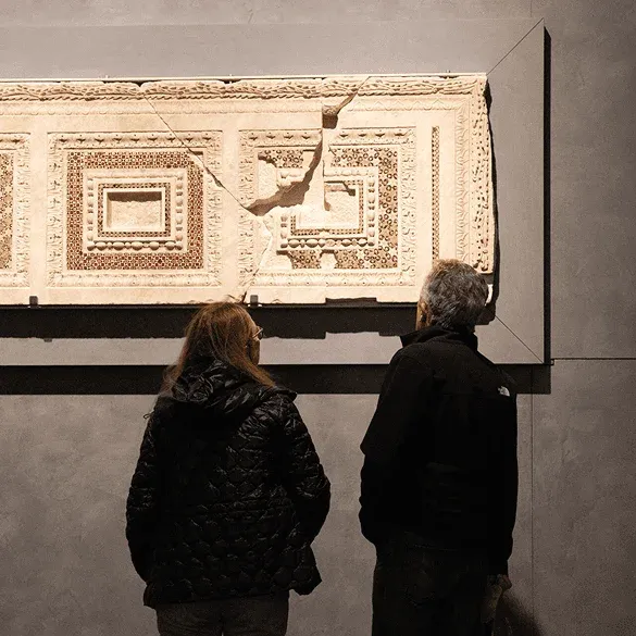 Visitors viewing historical relief at Opera del Duomo Museum Florence
