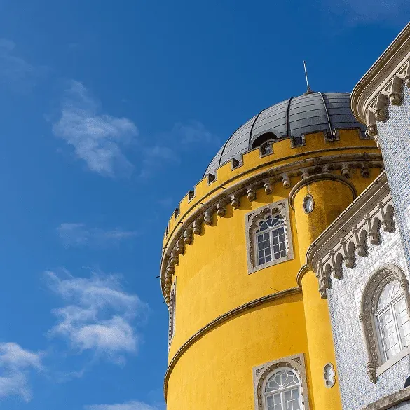 Gelbe Kuppel des Palacio Nacional da Pena in Sintra mit romantischer Fassade und blauem Himmel.