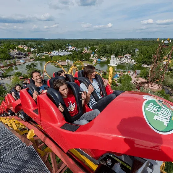 Visitantes disfrutando de una montaña rusa con vistas panorámicas del Parc Astérix