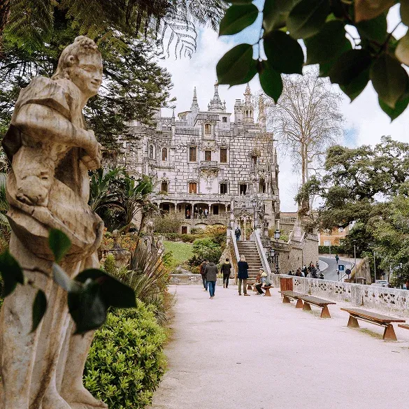 Zugang zum Palast von Quinta da Regaleira zwischen Gärten, Skulpturen und Vegetation in Sintra.