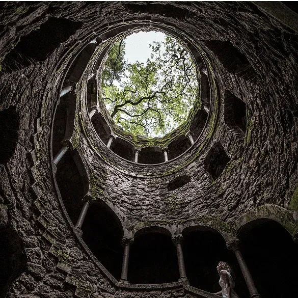 Blick vom Inneren des Initiationsbrunnens von Quinta da Regaleira in Sintra, mit der spiralförmigen Steintreppe.