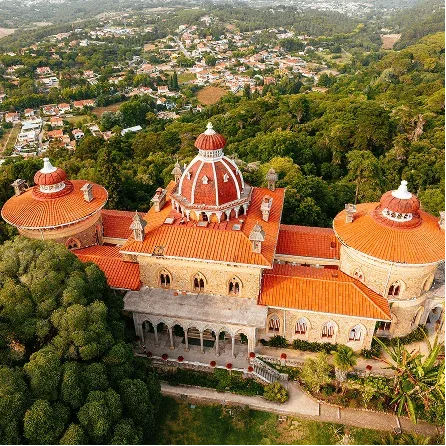 Aerial view of Monserrate Palace in Sintra surrounded by lush gardens and forest, one of the most beautiful historic estates in Portugal.