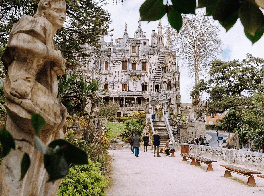 Visitors walking through the gardens of Quinta da Regaleira towards the palace in Sintra