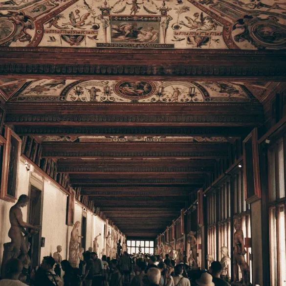 Pasillo principal de la Galería Uffizi con visitantes recorriendo las salas del museo.