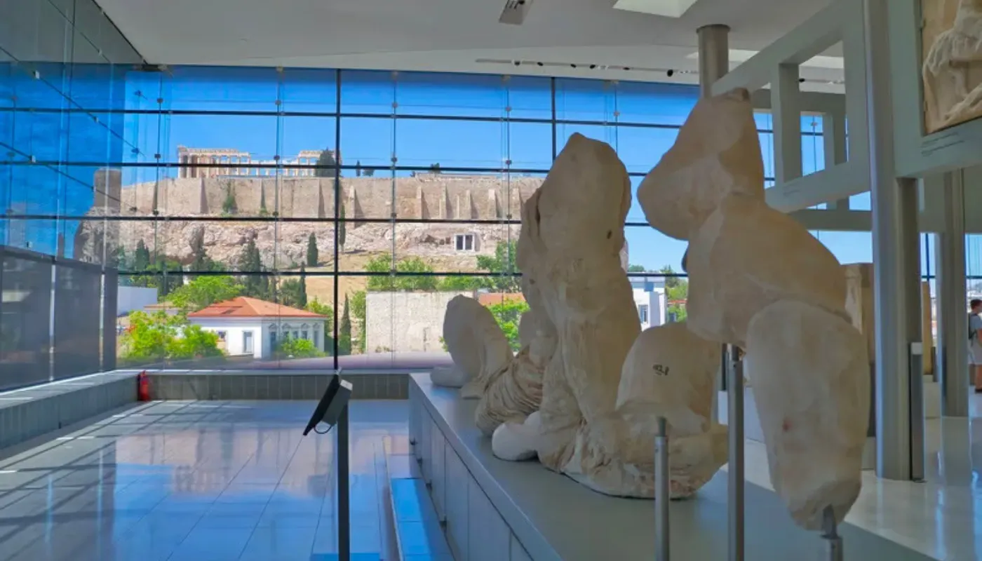 Archaeological sculptures of the Acropolis Museum with views of the Acropolis hill in Athens.