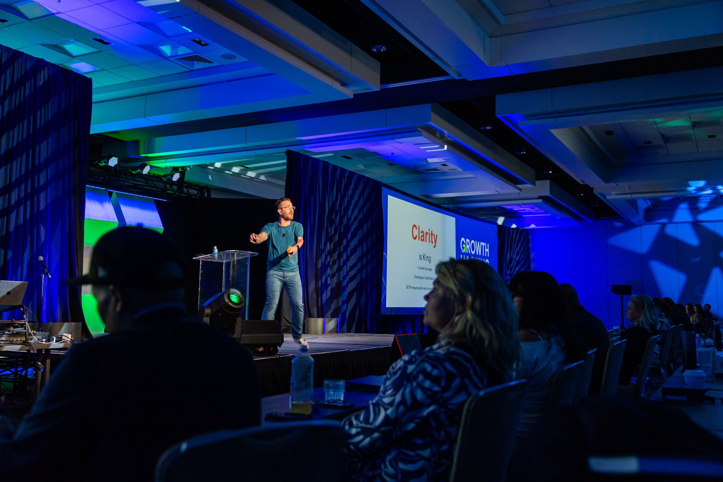 Brian Bogert speaking on stage with 'Clarity is King' slide at Growth Hacking Live