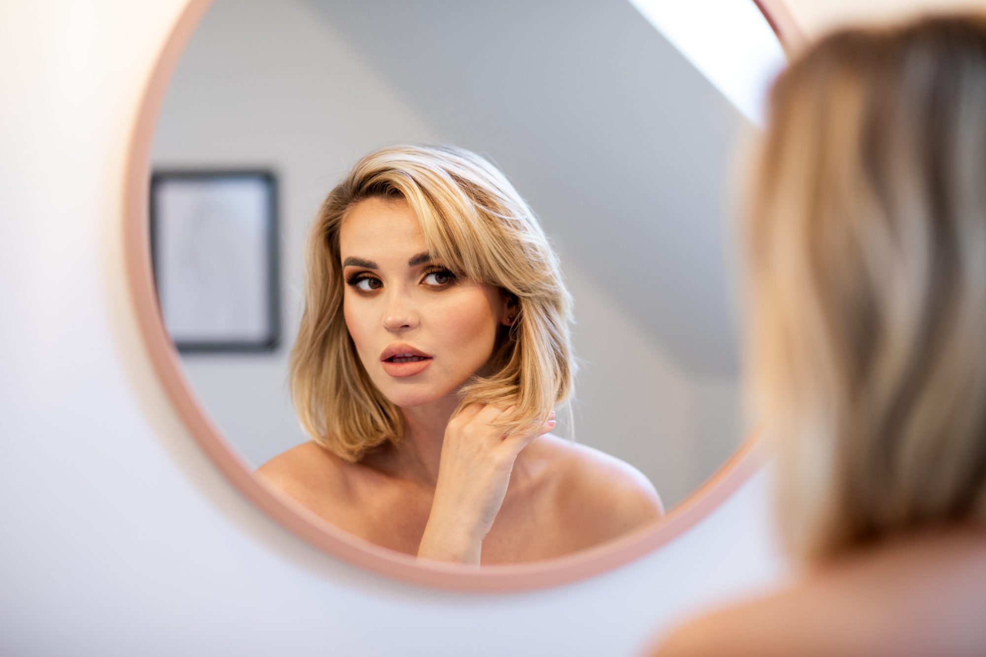 Checking hair young woman looking mirror in bathroom