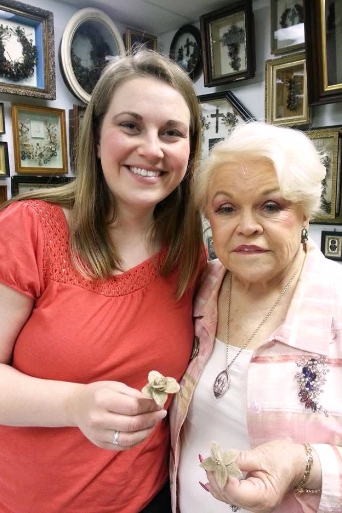 In this photo provided by Lindsay Evans, Evans and her grandmother, Leila Cohoon, hold hair flowers made from Evans’ son’s hair at Leila’s Hair Museum in Independence, Miss. (Lindsay Evans via AP)