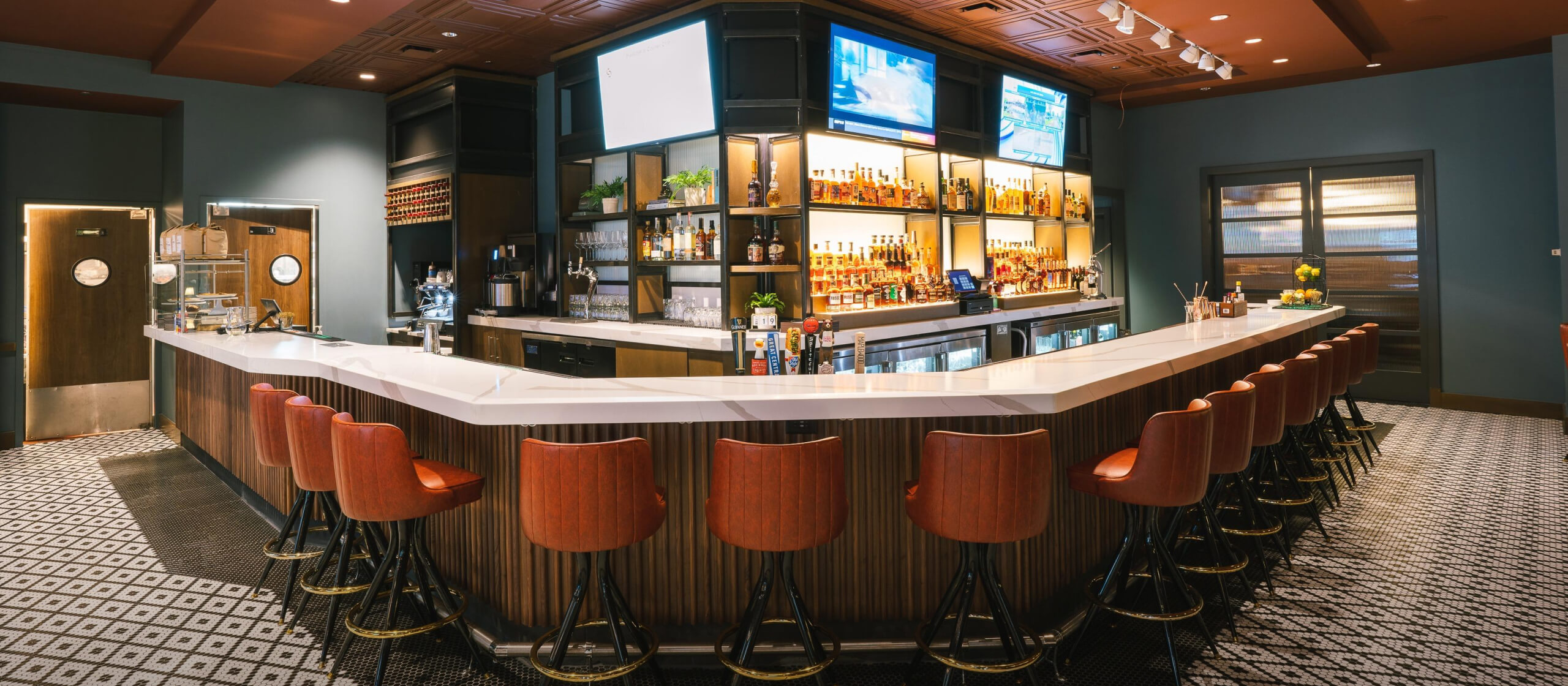 An image of a bar with multiple hightop brown chairs around it.