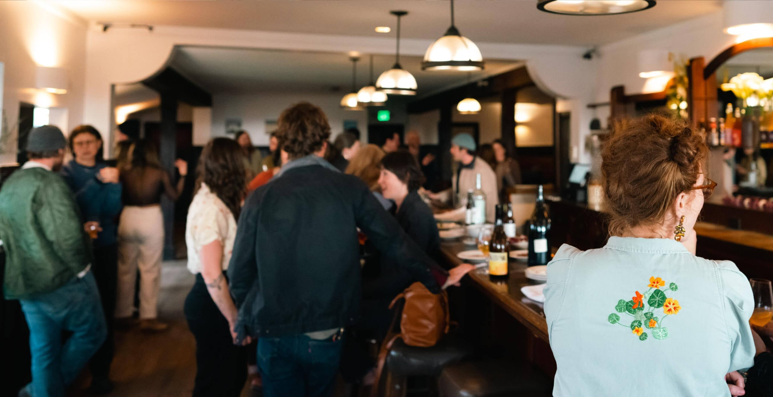 An image of various people waiting and talking in a bar.