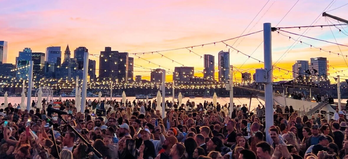 A crowd of people attending a concert at dusk.
