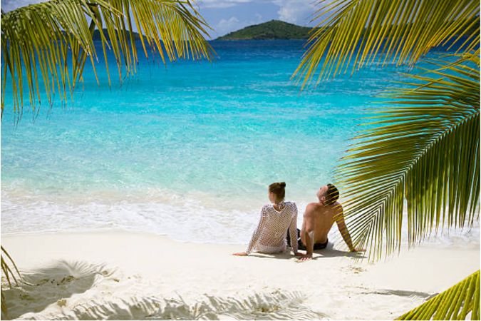 couple sitting on sands at during Caribbean vacation