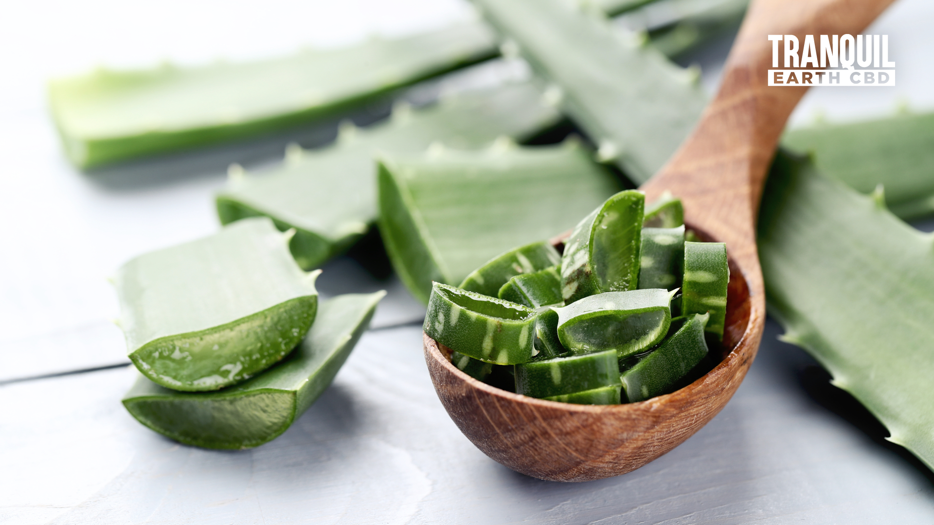 pieces of aloe vera leaves in a wooden spoon at center