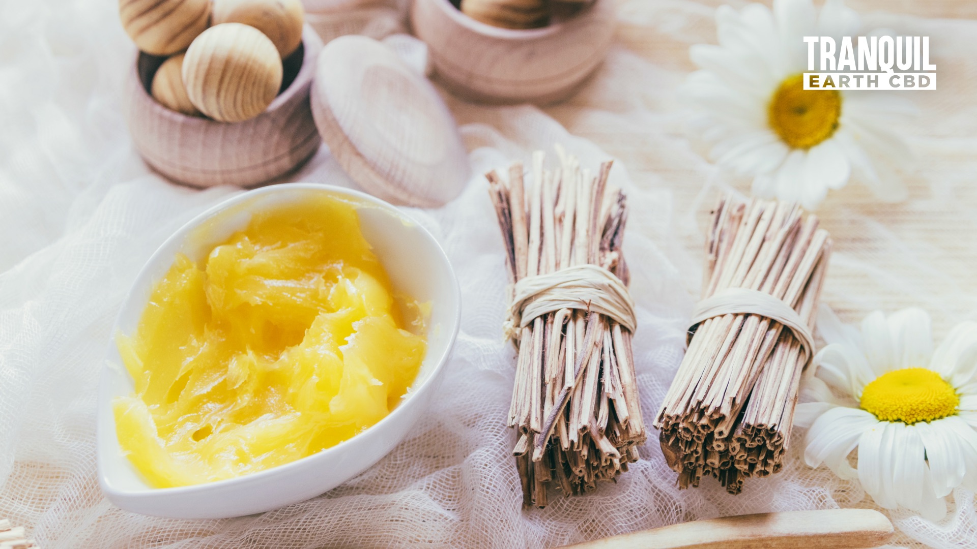 shea butter in a bowl on the left with stick bundles on the right and at center